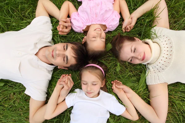 Parents avec des enfants couchés sur l'herbe, vue du haut, tête à la hée — Photo