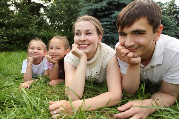 Семья из четырех человек лежит на траве и смотрит — стоковое фото