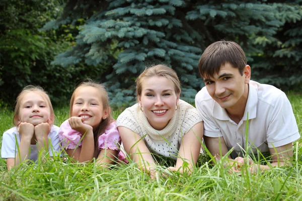 Семья из четырех человек лежит на траве и смотрит — стоковое фото