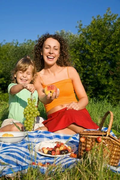 Pretty Little Girl y las mujeres jóvenes mantiene en la mano frutas en picni — Foto de Stock