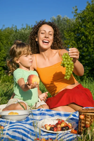 Sevimli küçük kız ve genç kadınlar sürekli elinde meyve picni üzerinde — Stok fotoğraf