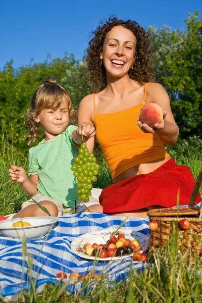 Söt liten flicka och unga kvinnor håller i hand frukter på picknick — Stockfoto