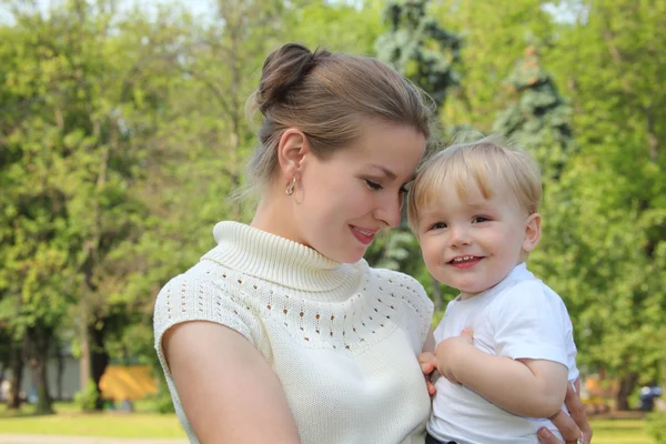 Äiti pitää vauvaa käsissä ulkona kesällä — kuvapankkivalokuva