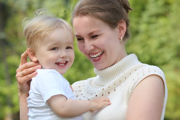 Moeder houden baby op handen buiten in de zomer en ziet er op hij — Stockfoto