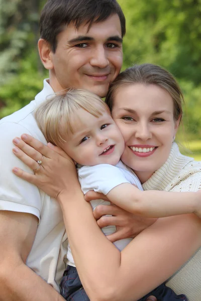 Родители держат ребенка на руках летом на открытом воздухе — стоковое фото