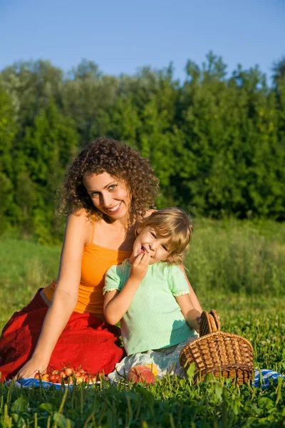Szép kis lány és fiatal nők eszik vadcseresznye piknik — Stock Fotó