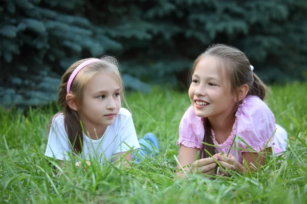 Twee meisjes liggen op gras in de zomer — Stockfoto