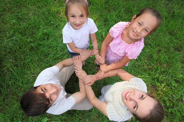 Ouders met kinderen staan hebben de handen ineen geslagen kruiselings, om te — Stockfoto
