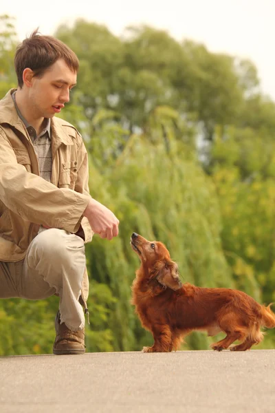 Νεαρός άνδρας και το αξιολάτρευτο dachshund εξωτερική — Φωτογραφία Αρχείου