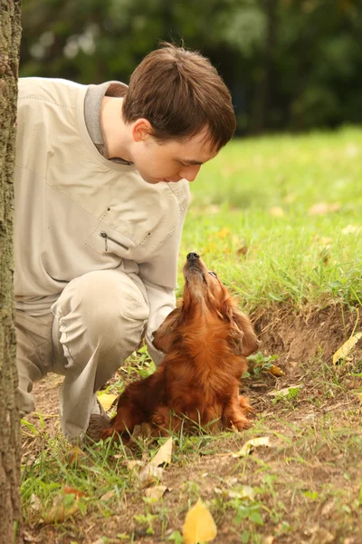 Jovem e seu adorável dachshund ao ar livre olha em cada othe — Fotografia de Stock