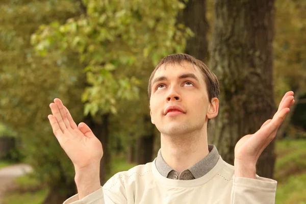 Молодой человек молится летом на открытом воздухе — стоковое фото