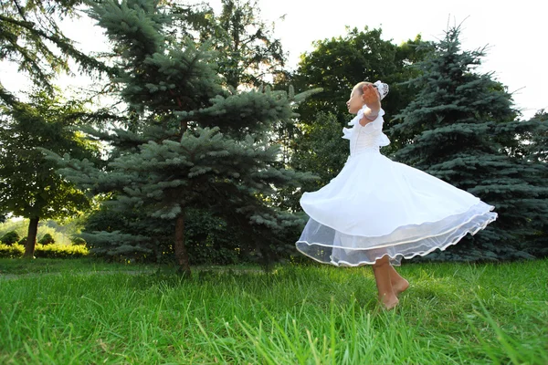 Girl in white dress dances on lawn — Stock Photo, Image