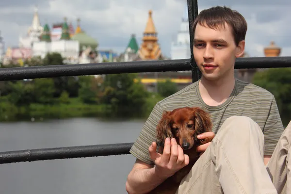 Νεαρός άνδρας κρατά είδος γερμανικού κυνηγετικού σκύλου στα χέρια εξωτερική το καλοκαίρι — Φωτογραφία Αρχείου