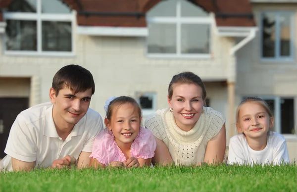 Vierköpfige Familie liegt auf Gras gegen Haus — Stockfoto