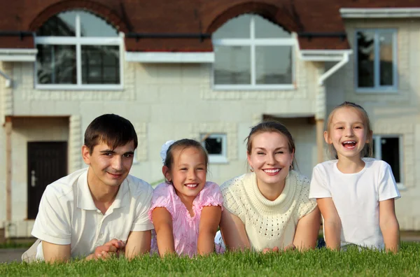 Vierköpfige Familie liegt auf Gras gegen Haus — Stockfoto