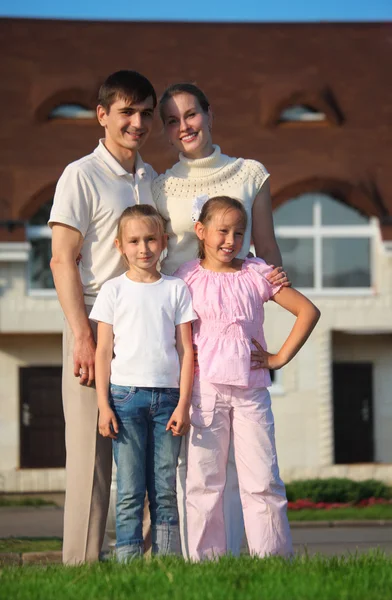 Vierköpfige Familie steht auf Gras gegen Haus — Stockfoto