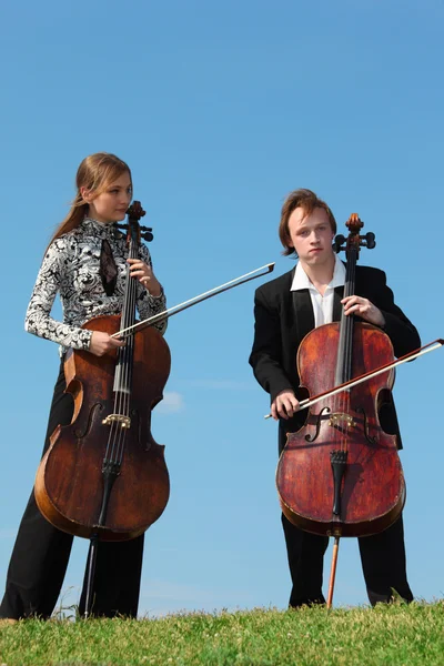 Two musicians play violoncellos against sky — Stock Photo, Image