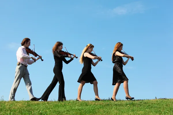 Four musicians go and playing violins against sky — Stock Photo, Image