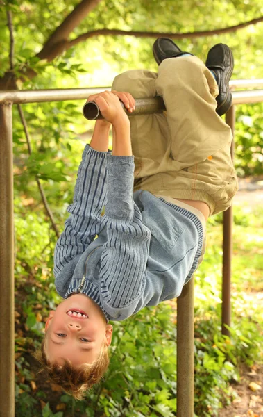 Boy hangs on bars headfirst — Stock Photo, Image