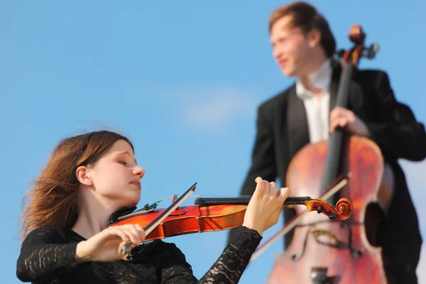 Violinist and violoncellist play against sky — Stock Photo, Image