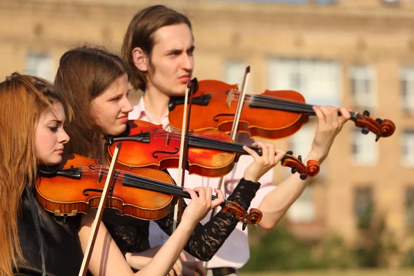 Трио скрипачей играет на открытом воздухе — стоковое фото