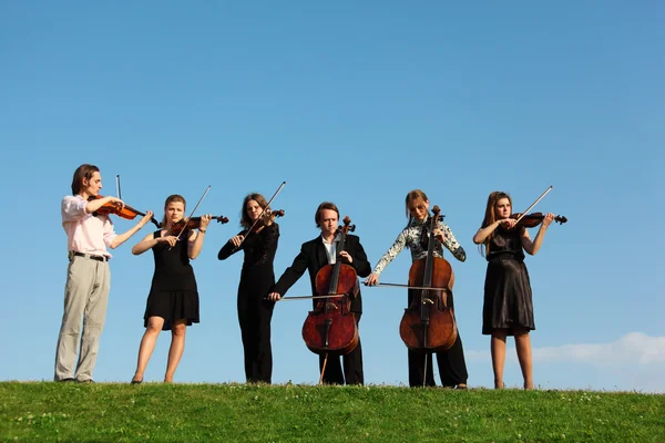 Шесть музыкантов играют на скрипках против неба — стоковое фото