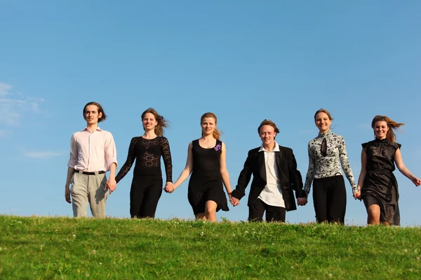 Six friends go on meadow having joined hands — Stock Photo, Image