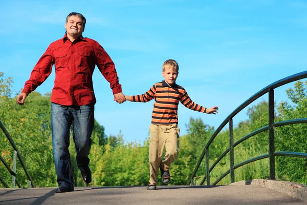 Hombre y niño corren en el puente en verano —  Fotos de Stock