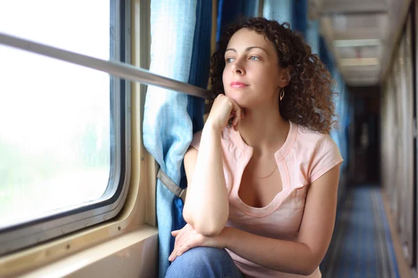 Young woman looks in train window — Stock Photo, Image