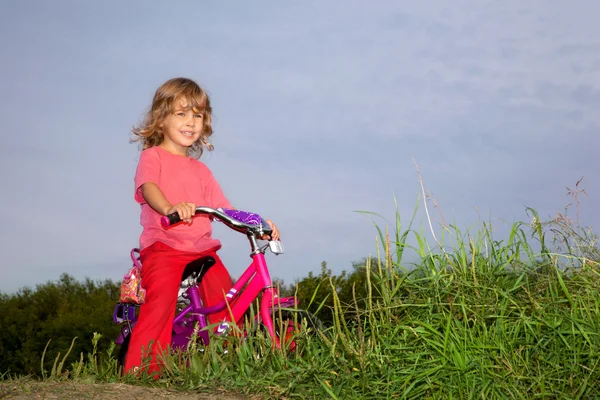 Kudrnatá dívka biker spočívá v poli — Stock fotografie