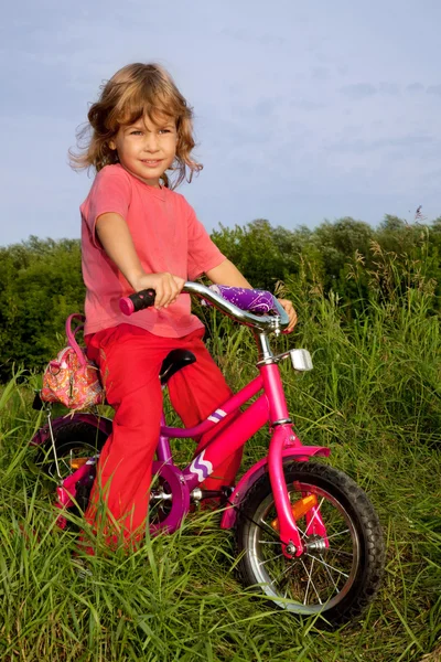 Kudrnatá dívka biker spočívá v poli — Stock fotografie