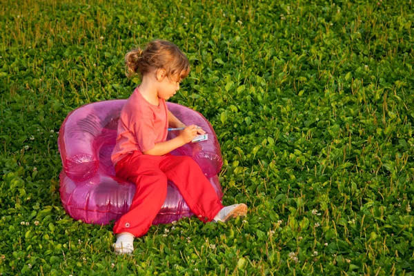Joven escritura chica se sienta en inflable sillón — Foto de Stock