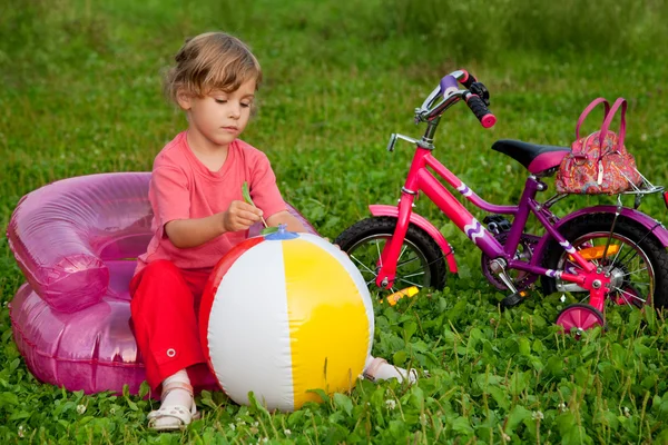 Jovem menina senta-se na poltrona inflável na frente da bicicleta — Fotografia de Stock