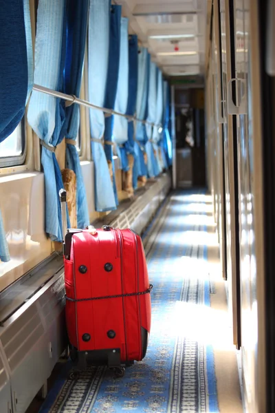 Červený kufr v koridoru železniční vagón — Stock fotografie
