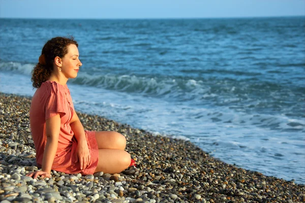 Jovem mulher senta-se em terra do mar — Fotografia de Stock