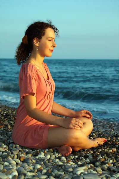 Młoda kobieta siedzi i medytacji na brzeg morza — Zdjęcie stockowe