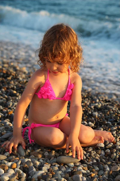 Klein meisje zit op strand — Stockfoto