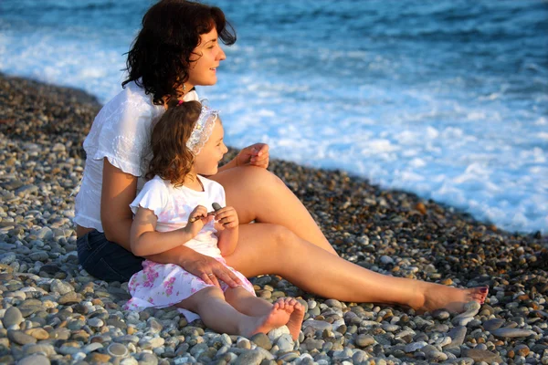 Мать с дочерью сидит на берегу моря — стоковое фото
