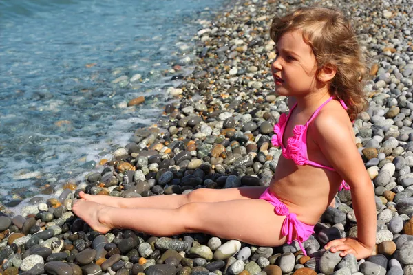 Little girl sits on beach — Stock Photo, Image