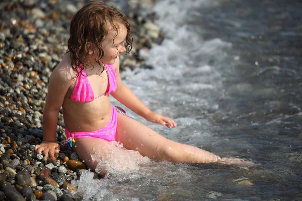 小女孩坐在岸上在波浪中 — 图库照片