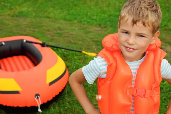 Boy and inflatable boat on lawn — Stock Photo, Image