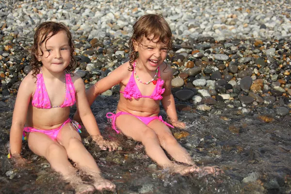 Zwei kleine Mädchen sitzen an Land im Wasser — Stockfoto
