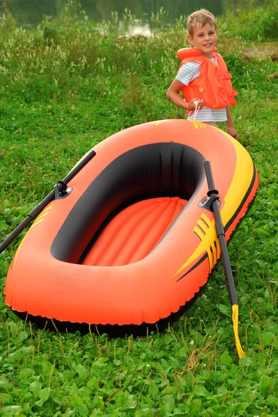 Мальчик и надувная лодка на газоне — стоковое фото