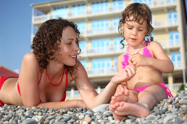 Mother with daughter on pebble in swimwear — Stock Photo, Image