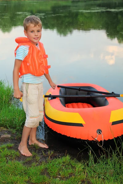 Boy and inflatable boat ashore — Stock Photo, Image