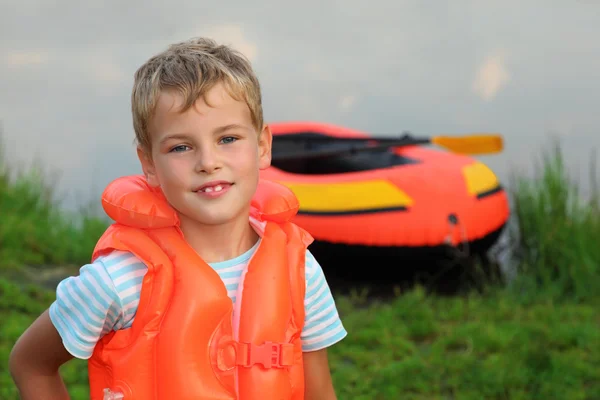 Мальчик и надувная лодка на берегу — стоковое фото