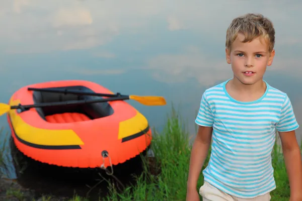 Chłopiec i nadmuchiwane boat lądzie — Zdjęcie stockowe