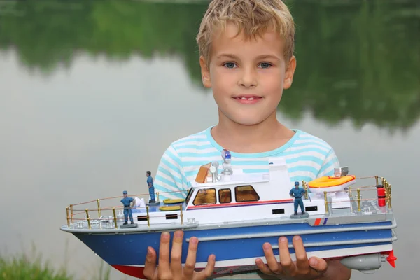 Chłopiec z zabawkami statku w ręce na lądzie — Zdjęcie stockowe
