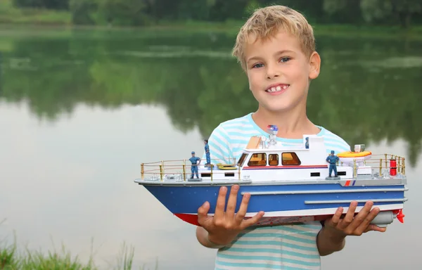 Мальчик с игрушечным кораблем в руках на берегу — стоковое фото