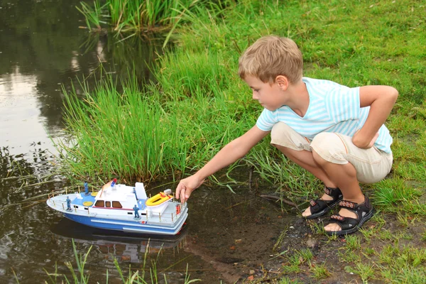 Boy sends toy ship in floating — Stock Photo, Image